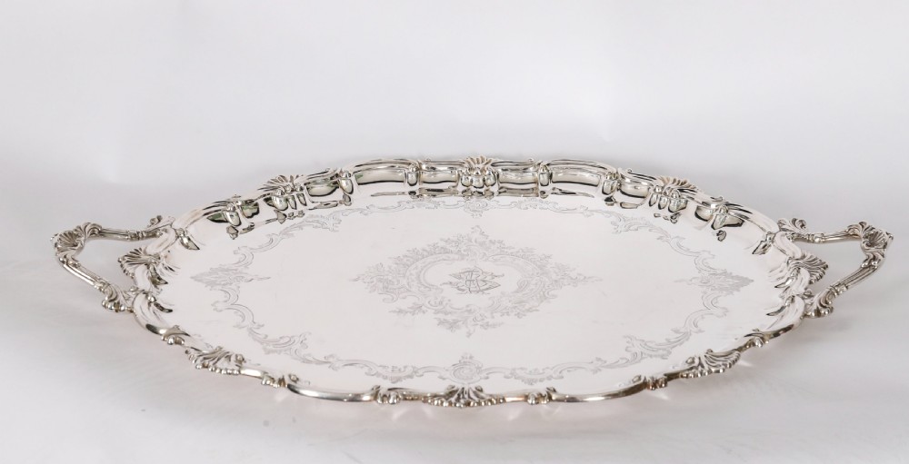 An oval Victorian silver plated serving tray featuring engraved scrollwork, cast shell borders, and dual side handles. View XV