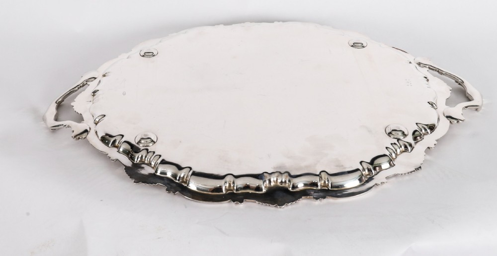 An oval Victorian silver plated serving tray featuring engraved scrollwork, cast shell borders, and dual side handles. View XVI
