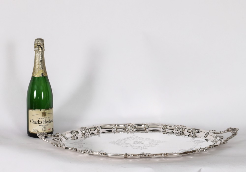 An oval Victorian silver plated serving tray featuring engraved scrollwork, cast shell borders, and dual side handles. View XIX