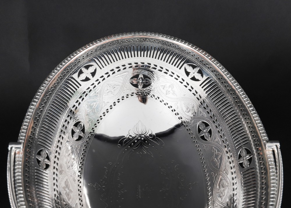 An antique silver-plated oval fruit basket featuring delicate pierced metalwork, engraved geometric motifs, a beaded pedestal foot, and a tall arched handle. View XII
