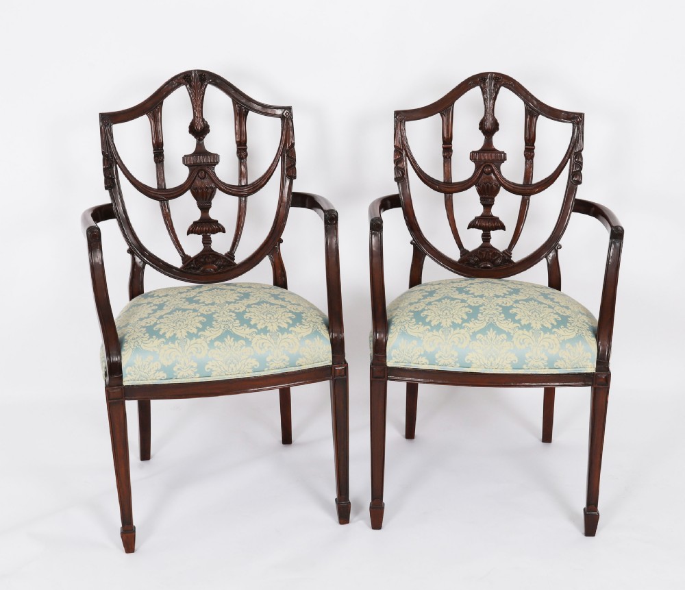 A pair of 20th-century mahogany Federal Revival armchairs featuring carved shield backs with central urn splats and blue patterned damask seats.
