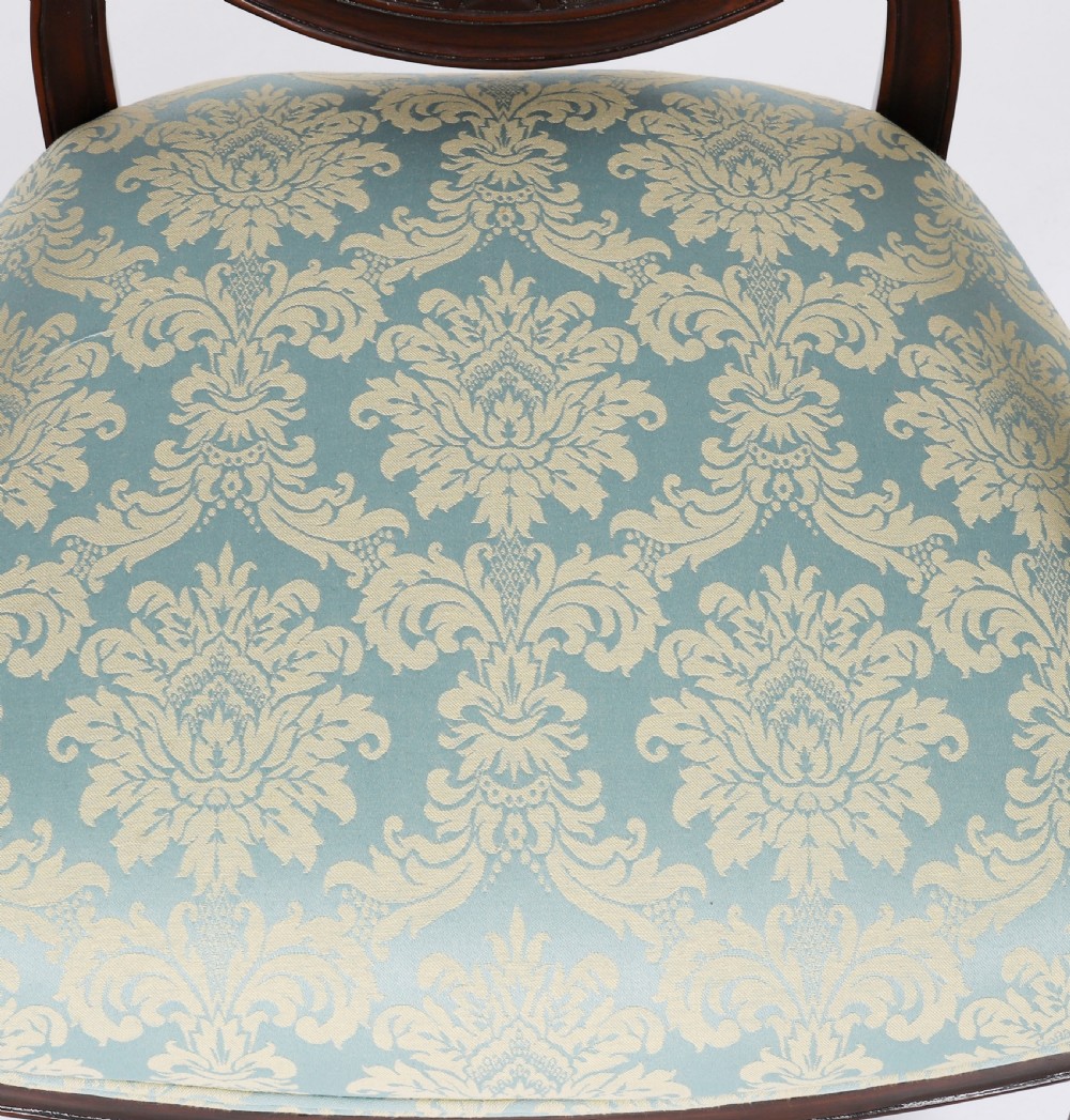 A pair of 20th-century mahogany Federal Revival armchairs featuring carved shield backs with central urn splats and blue patterned damask seats. View VIII