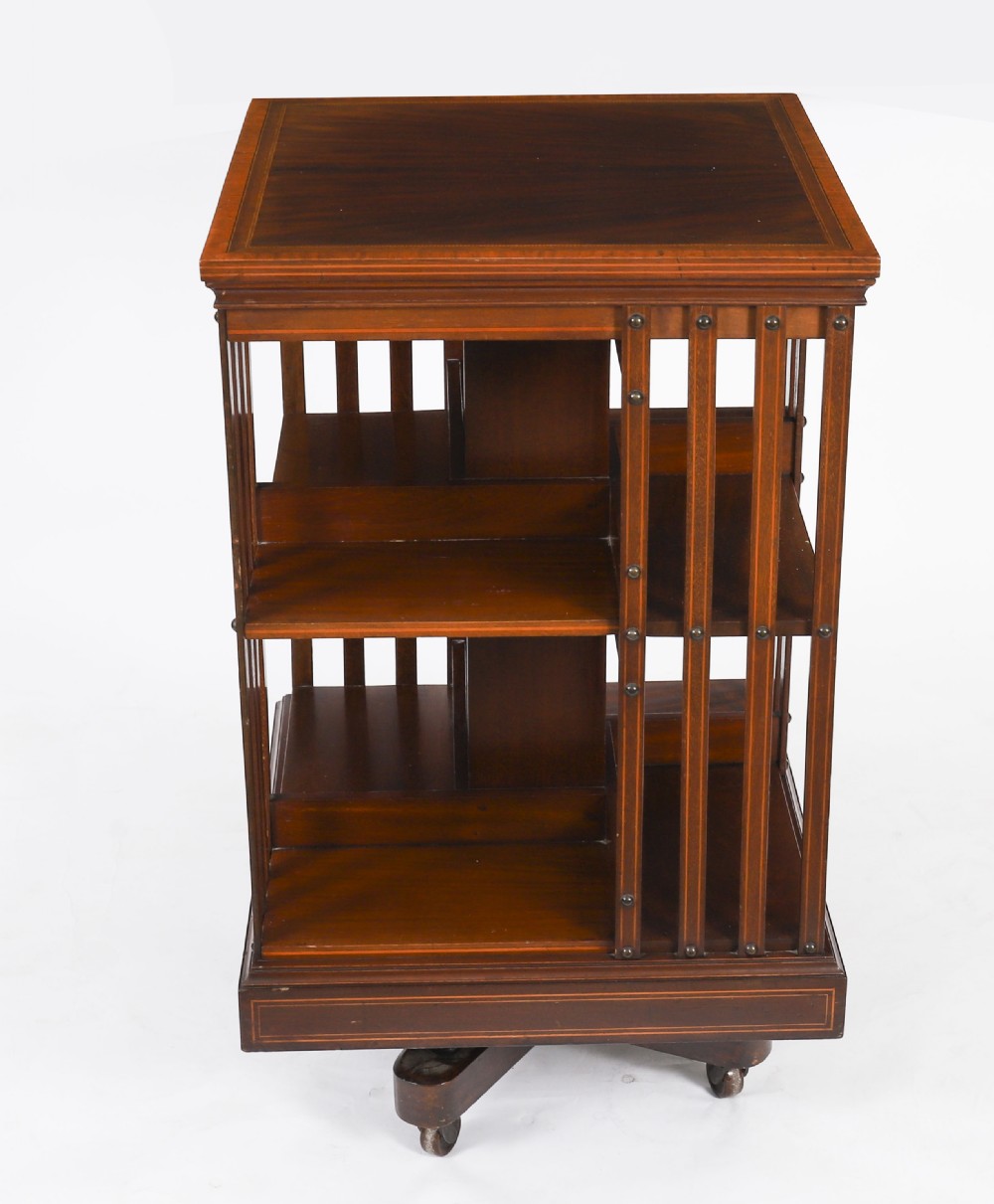An Edwardian flame mahogany two-tier revolving bookcase featuring satinwood crossbanding, slatted sides with brass studs, and a rotating base on castors. View III