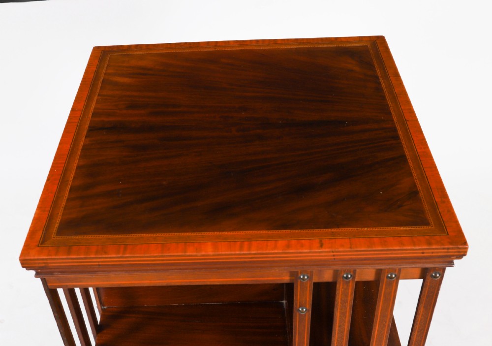 An Edwardian flame mahogany two-tier revolving bookcase featuring satinwood crossbanding, slatted sides with brass studs, and a rotating base on castors. View IV