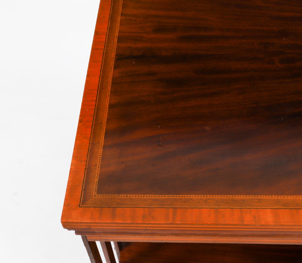An Edwardian flame mahogany two-tier revolving bookcase featuring satinwood crossbanding, slatted sides with brass studs, and a rotating base on castors. View V