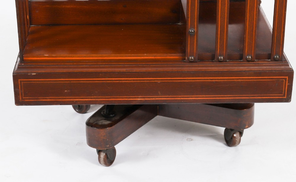 An Edwardian flame mahogany two-tier revolving bookcase featuring satinwood crossbanding, slatted sides with brass studs, and a rotating base on castors. View VIII
