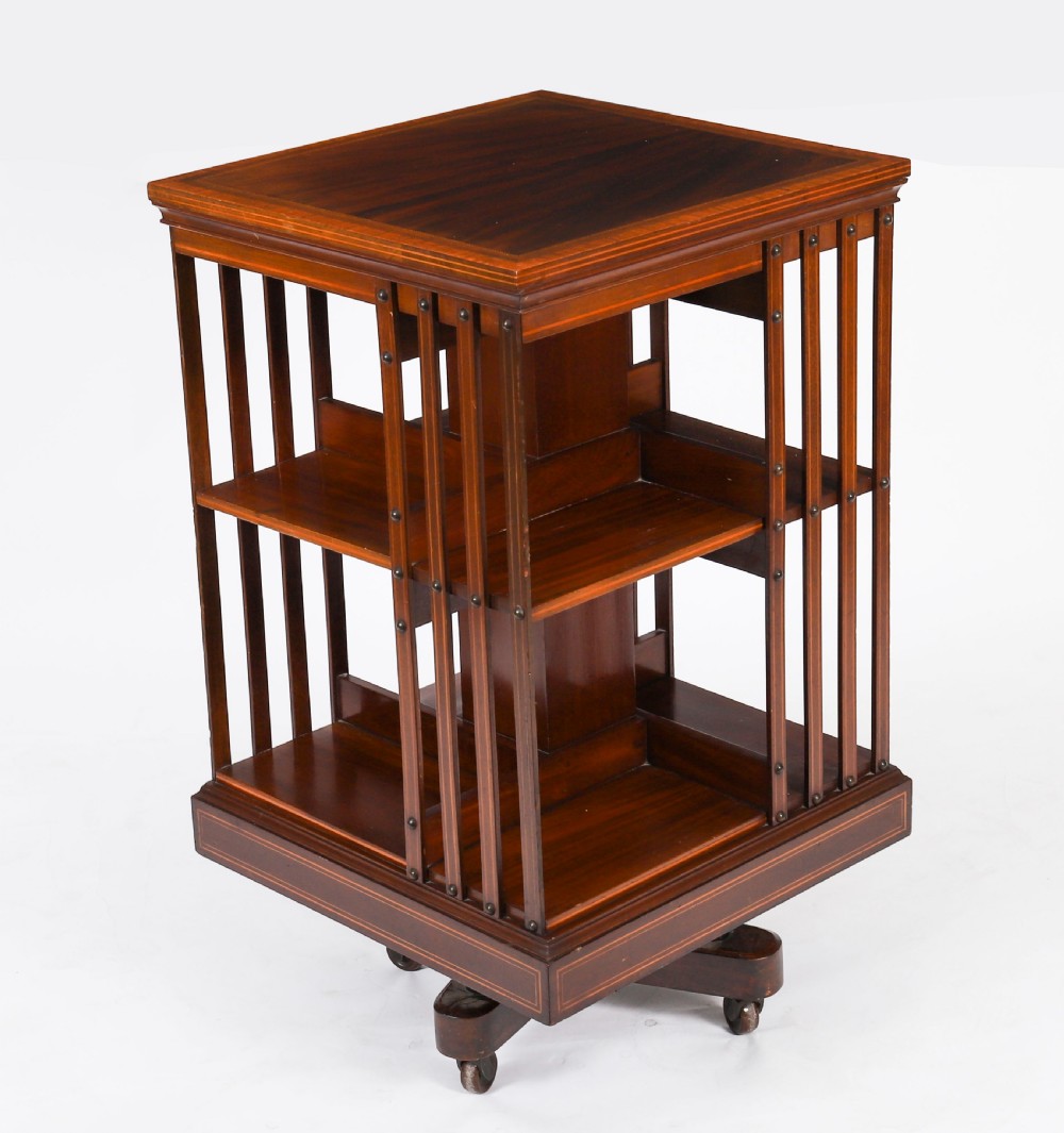 An Edwardian flame mahogany two-tier revolving bookcase featuring satinwood crossbanding, slatted sides with brass studs, and a rotating base on castors. View IX