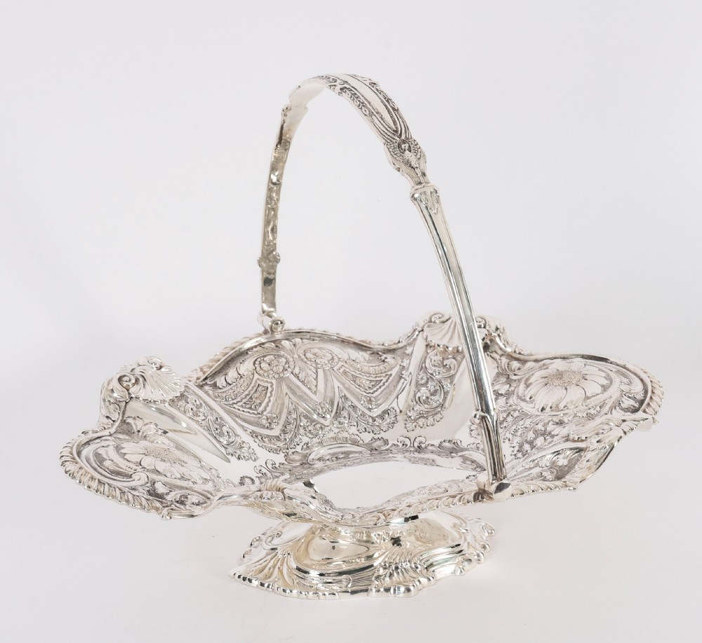 An ornate Victorian silver-plated fruit basket featuring chased floral motifs, a scalloped shell rim, a pedestal base, and a hinged overhead swing handle. View II