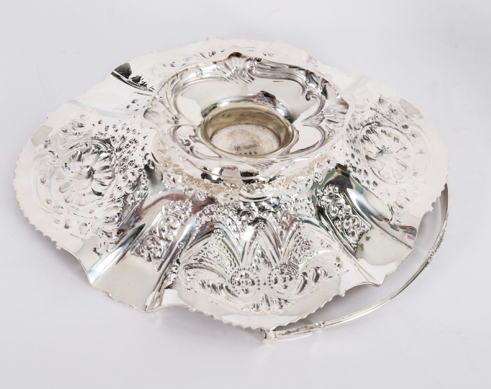 An ornate Victorian silver-plated fruit basket featuring chased floral motifs, a scalloped shell rim, a pedestal base, and a hinged overhead swing handle. View XVII
