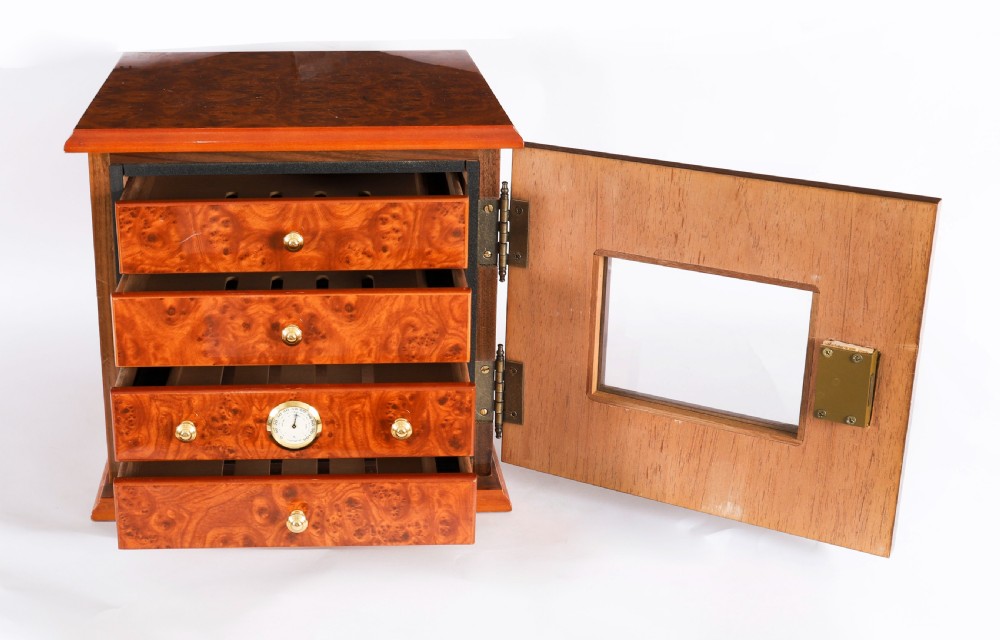 A square burr elm cigar humidor cabinet featuring a glass viewing window, brass hygrometer, front lock, and polished wood figure. View VI