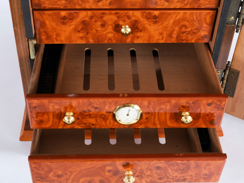 A square burr elm cigar humidor cabinet featuring a glass viewing window, brass hygrometer, front lock, and polished wood figure. View XI