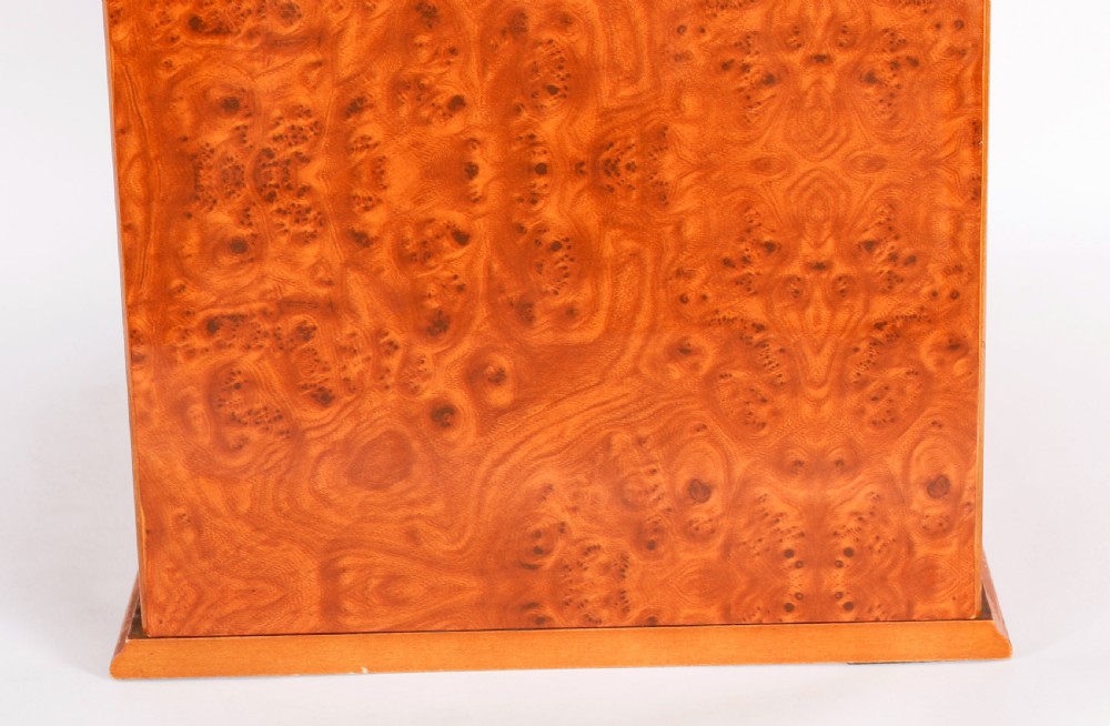 A square burr elm cigar humidor cabinet featuring a glass viewing window, brass hygrometer, front lock, and polished wood figure. View XV