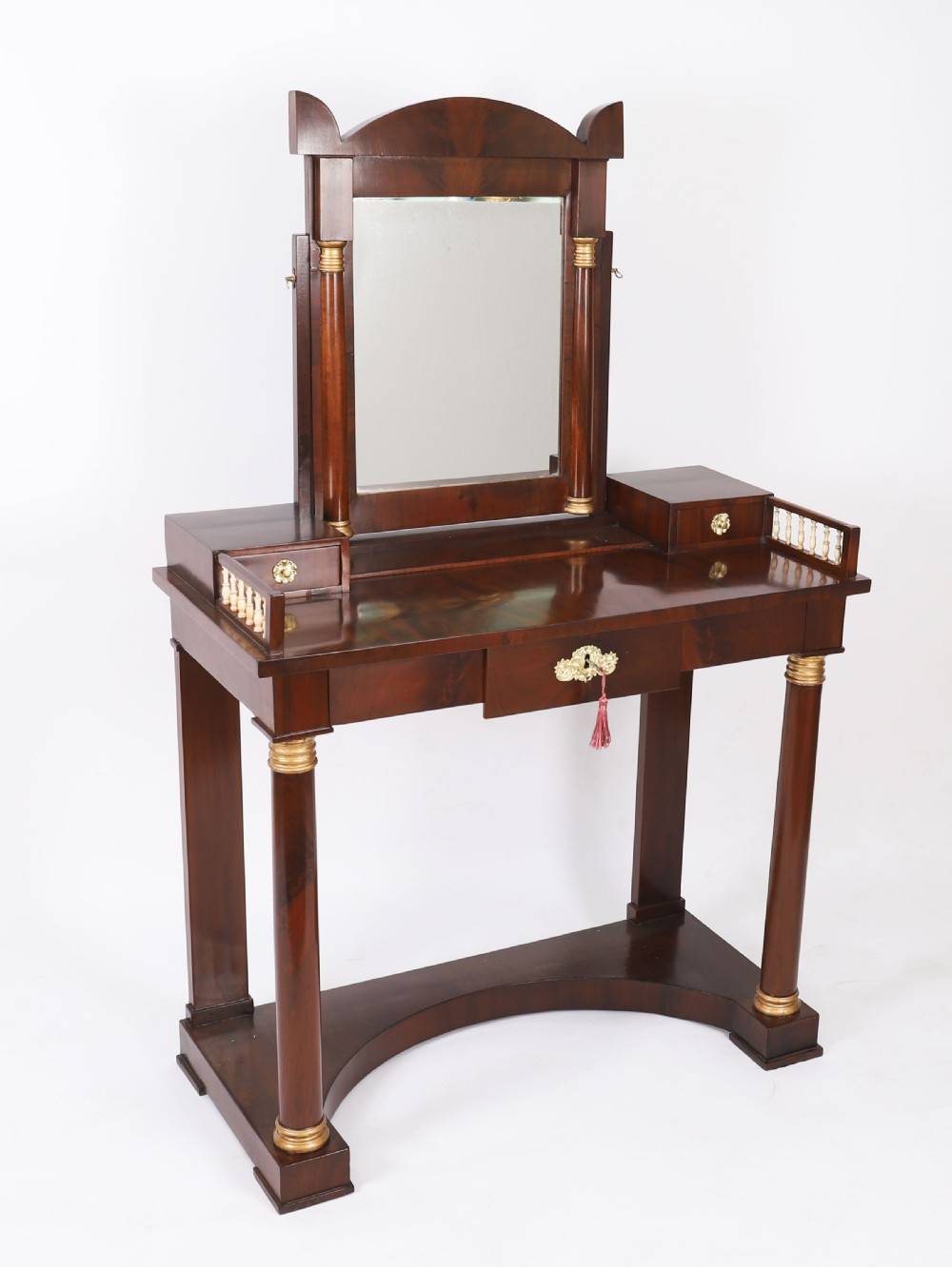A 19th-century French Empire mahogany dressing table with a central adjustable mirror, gilded column supports, small side drawers, and a lower curved stretcher.