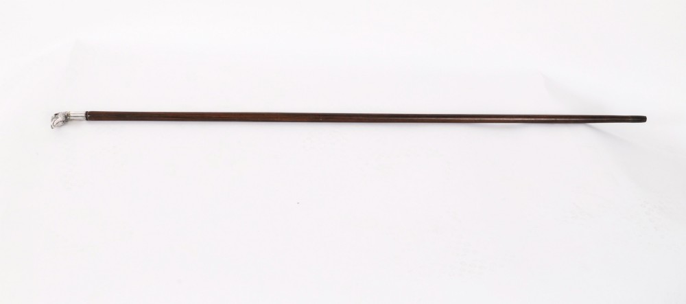 An antique silver walking stick handle sculpted in the form of a pheasant head with a red glass eye atop a dark wooden shaft. View II