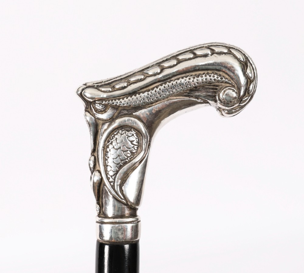 An antique French Art Nouveau walking cane featuring an ornate silver handle and a tapered black wooden shaft. View II