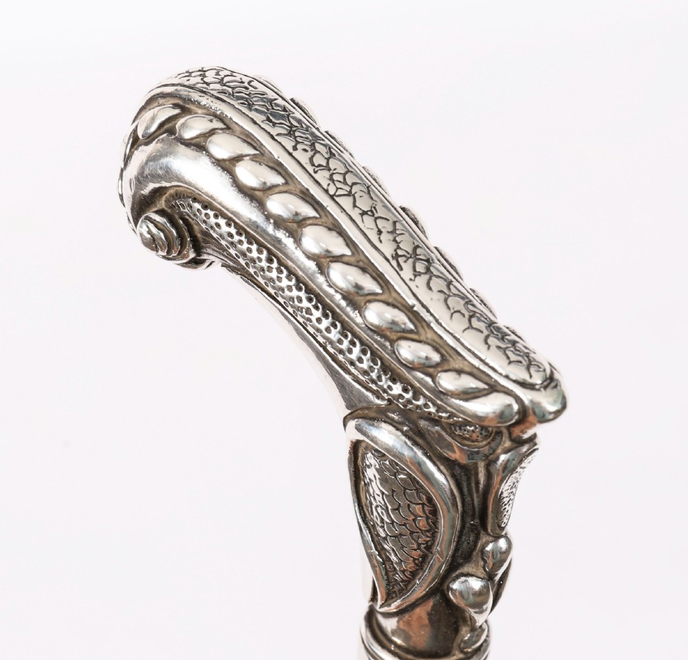 An antique French Art Nouveau walking cane featuring an ornate silver handle and a tapered black wooden shaft. View III