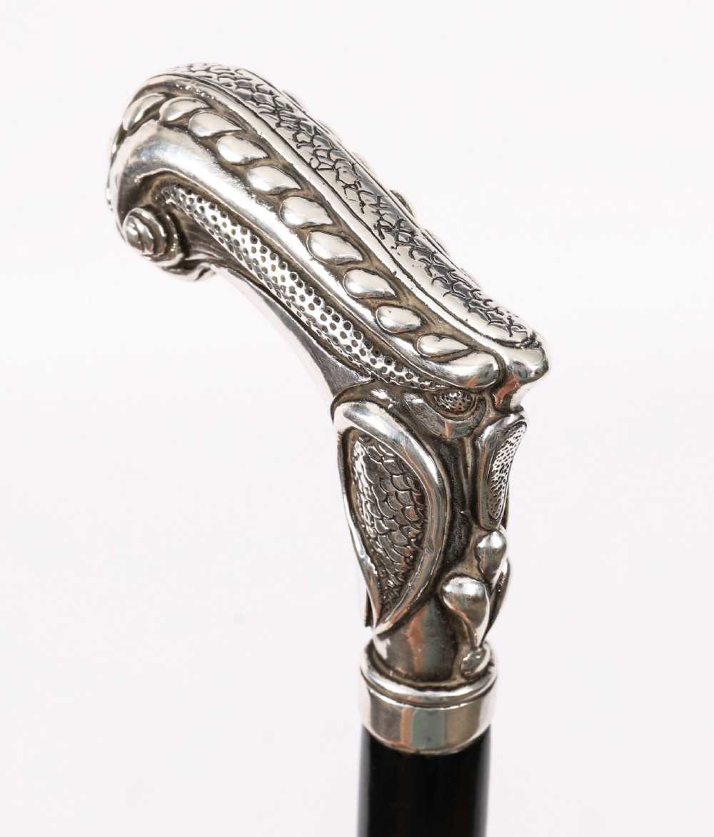 An antique French Art Nouveau walking cane featuring an ornate silver handle and a tapered black wooden shaft. View V