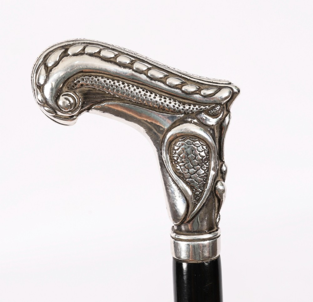 An antique French Art Nouveau walking cane featuring an ornate silver handle and a tapered black wooden shaft. View VII