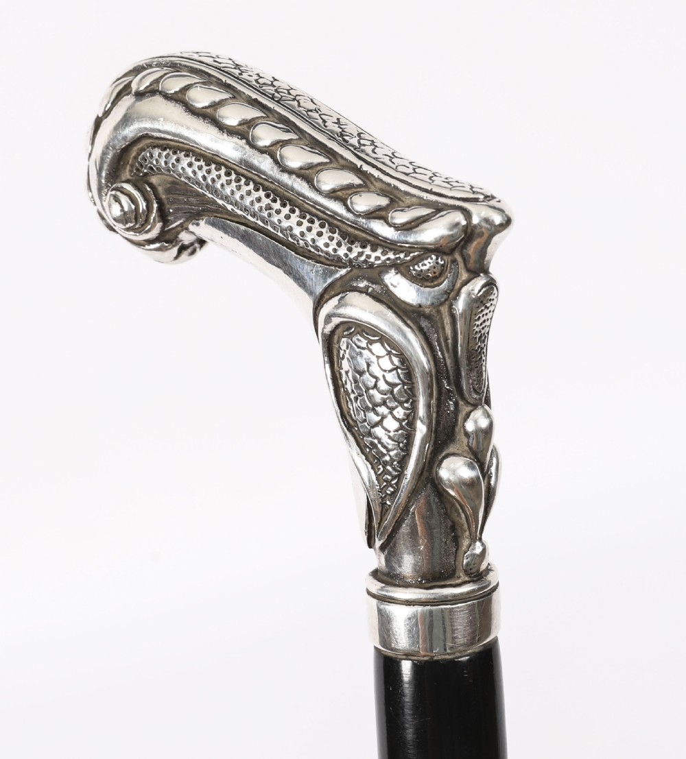 An antique French Art Nouveau walking cane featuring an ornate silver handle and a tapered black wooden shaft. View VIII