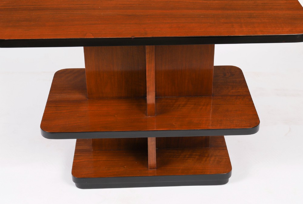 An antique Art Deco tiered walnut coffee table featuring rounded rectangular surfaces, central vertical dividers, and dark ebonised trim on a plain background. View VI