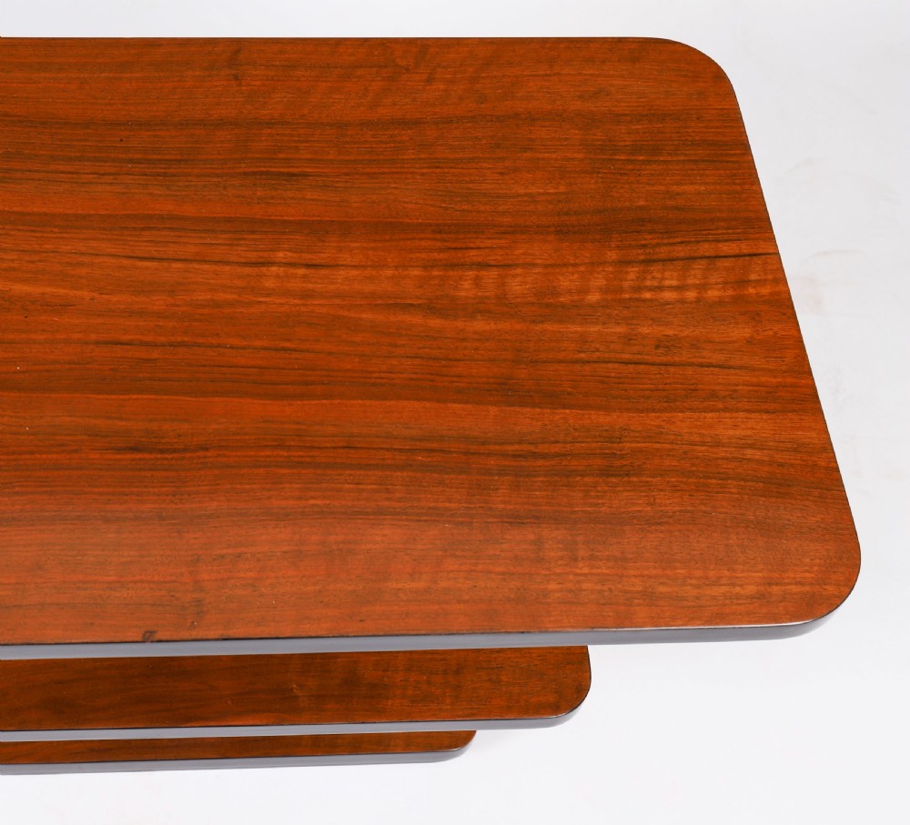 An antique Art Deco tiered walnut coffee table featuring rounded rectangular surfaces, central vertical dividers, and dark ebonised trim on a plain background. View IX