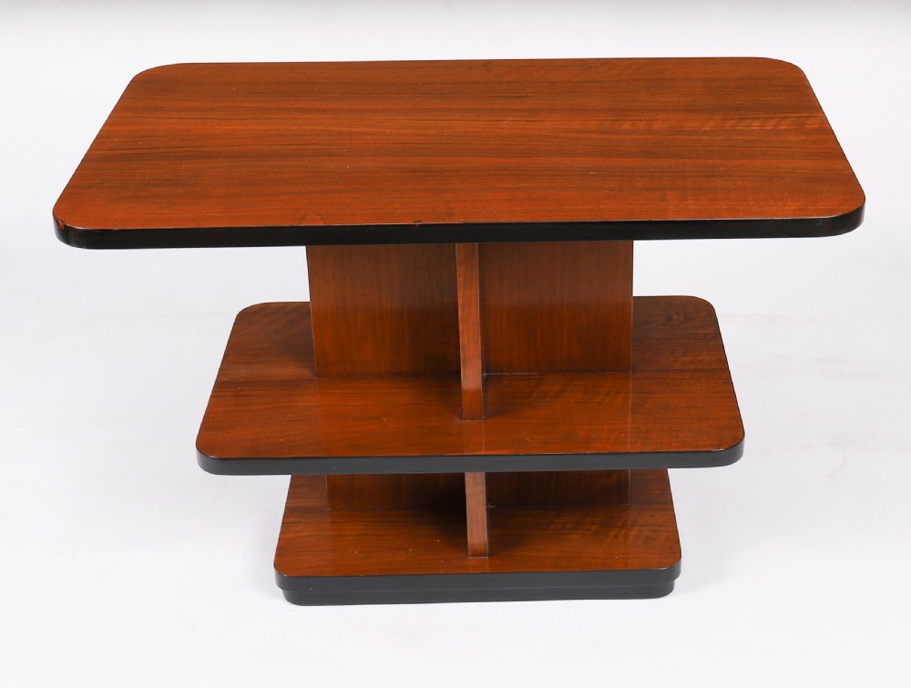 An antique Art Deco tiered walnut coffee table featuring rounded rectangular surfaces, central vertical dividers, and dark ebonised trim on a plain background. View X