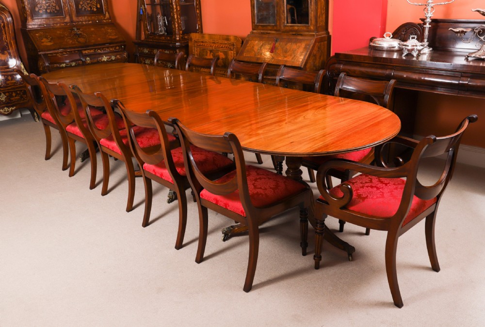 A long polished mahogany triple pillar dining table featuring splayed tripod bases fitted with brass claw feet and castors. View II