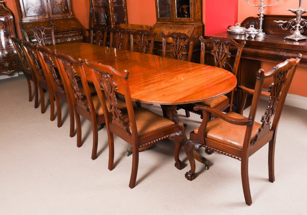 A long polished mahogany triple pillar dining table featuring splayed tripod bases fitted with brass claw feet and castors. View III