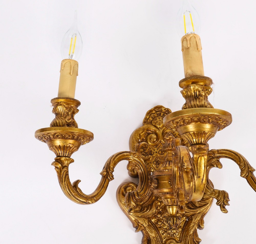 A pair of French gilt bronze three-arm wall sconces featuring scrolled foliate ornamentation and decorative backplates. View VII