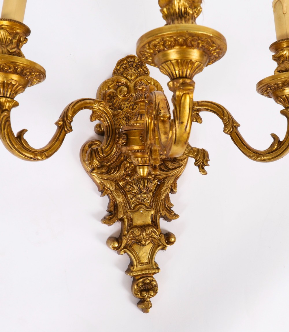 A pair of French gilt bronze three-arm wall sconces featuring scrolled foliate ornamentation and decorative backplates. View XI