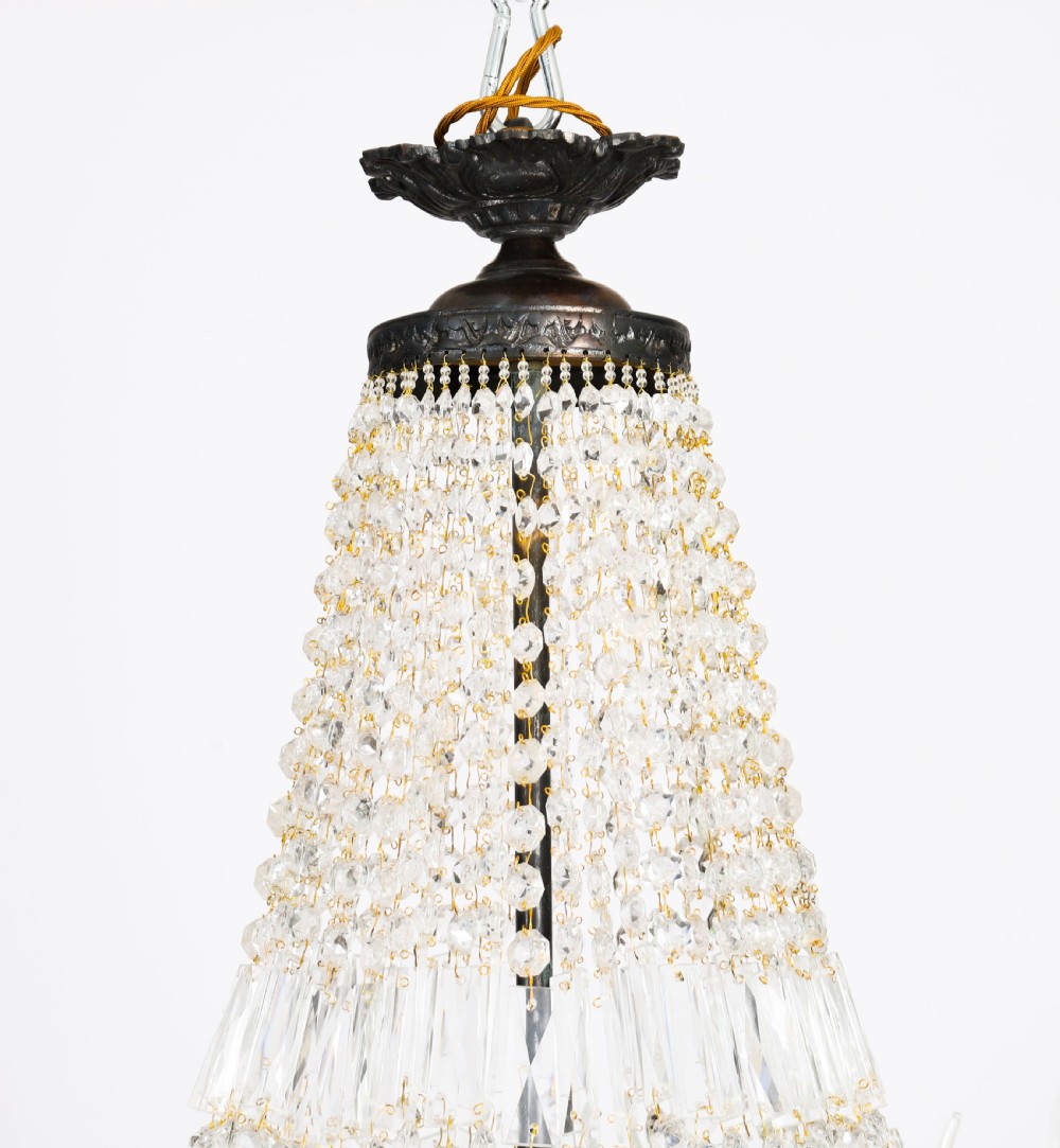 A large 1920s Louis Revival tent chandelier featuring an upper cone and lower basket of cut crystal beads set on a patinated bronze band with fourteen radiating candle arms. View XIV