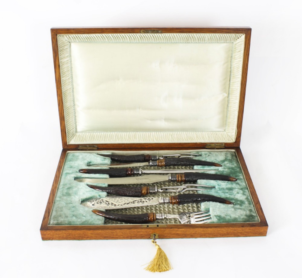 A 19th-century Victorian silver-plated carving and serving set with dark stag antler handles, displayed inside a silk and velvet lined wooden canteen box.