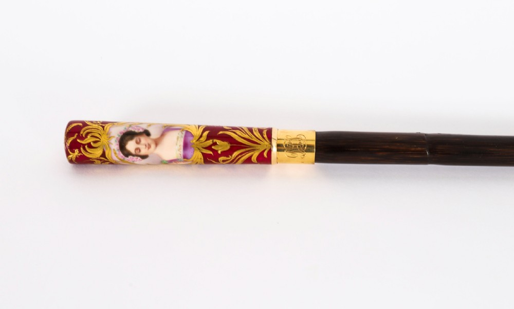A nineteenth-century French walking stick featuring a dark wood shaft, a gilt metal band, and a hand-painted porcelain pommel handle. View V