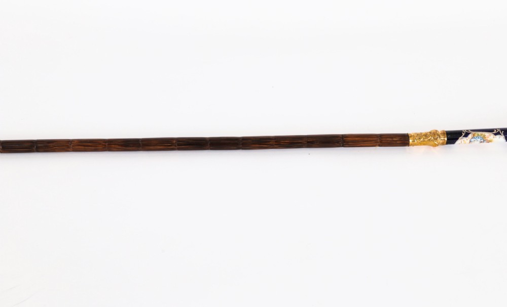 A nineteenth-century French walking cane featuring a dark wooden shaft, a concealed steel blade, and a gilt metal handle mounted with painted Sevres porcelain. View X