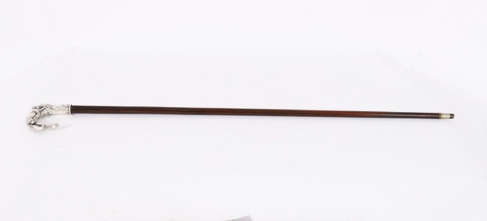 An antique walking stick featuring a detailed silver handle depicting a fox and hare, set atop a dark wood shaft with a metal ferrule.