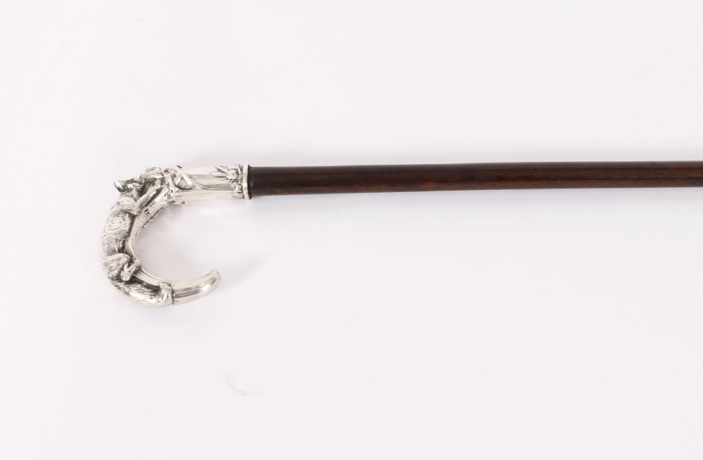 An antique walking stick featuring a detailed silver handle depicting a fox and hare, set atop a dark wood shaft with a metal ferrule. View IV