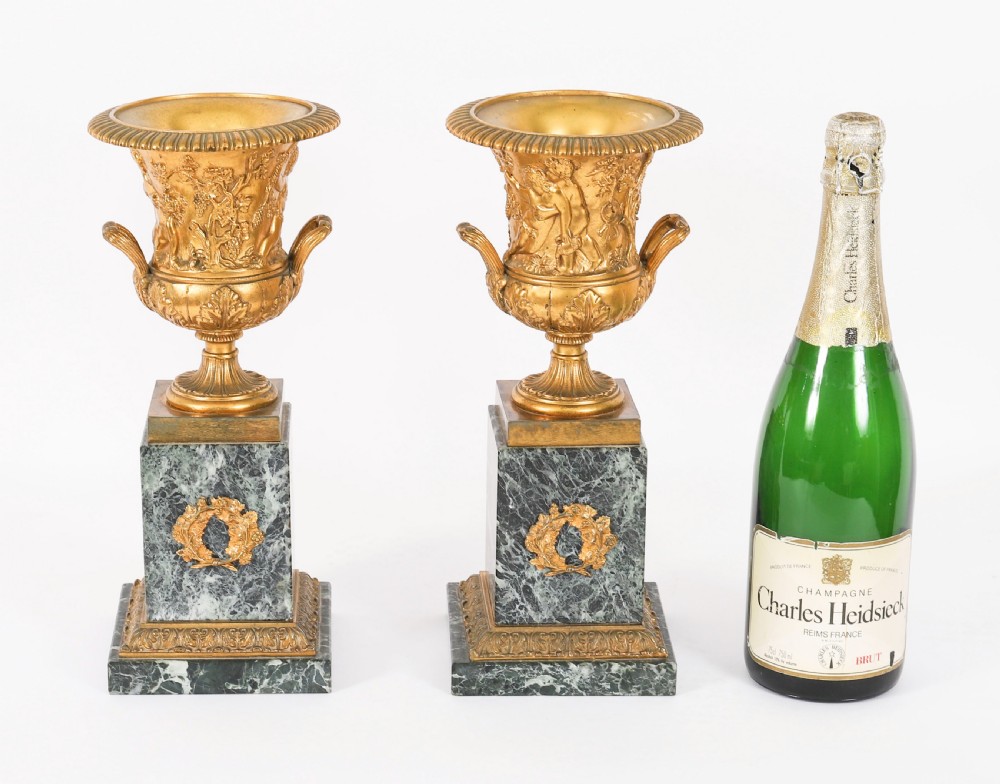 A pair of 19th-century French Grand Tour gilt bronze campana urns featuring classical figure reliefs, mounted on square green marble pedestal bases with gilt laurel wreaths. View XIX