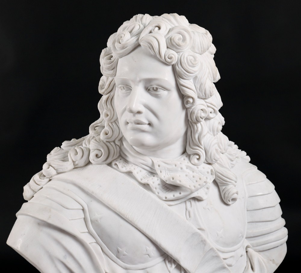 Carved white marble bust depicting a nobleman with long curled hair, lace cravat, and plate armour on a turned circular pedestal. View IV