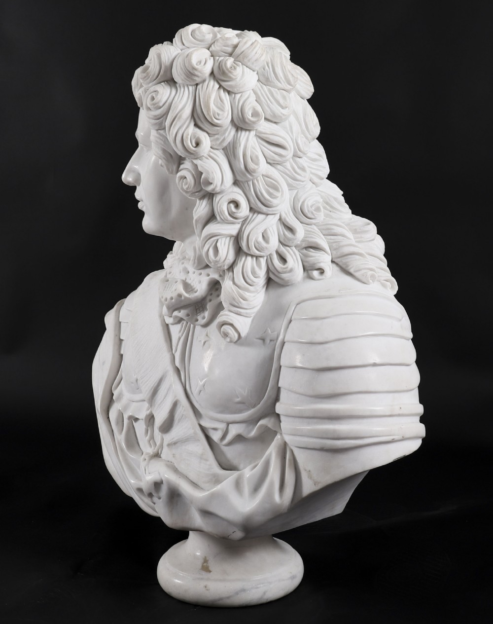 Carved white marble bust depicting a nobleman with long curled hair, lace cravat, and plate armour on a turned circular pedestal. View VI