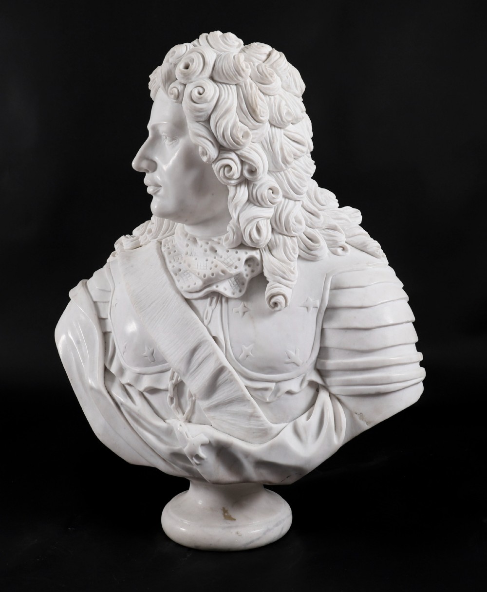 Carved white marble bust depicting a nobleman with long curled hair, lace cravat, and plate armour on a turned circular pedestal. View VIII