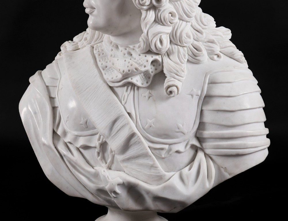 Carved white marble bust depicting a nobleman with long curled hair, lace cravat, and plate armour on a turned circular pedestal. View IX