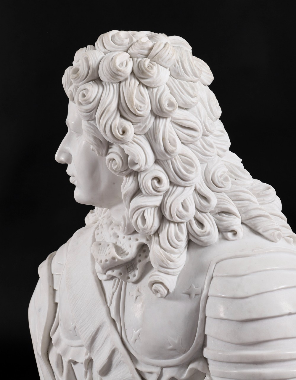 Carved white marble bust depicting a nobleman with long curled hair, lace cravat, and plate armour on a turned circular pedestal. View XII