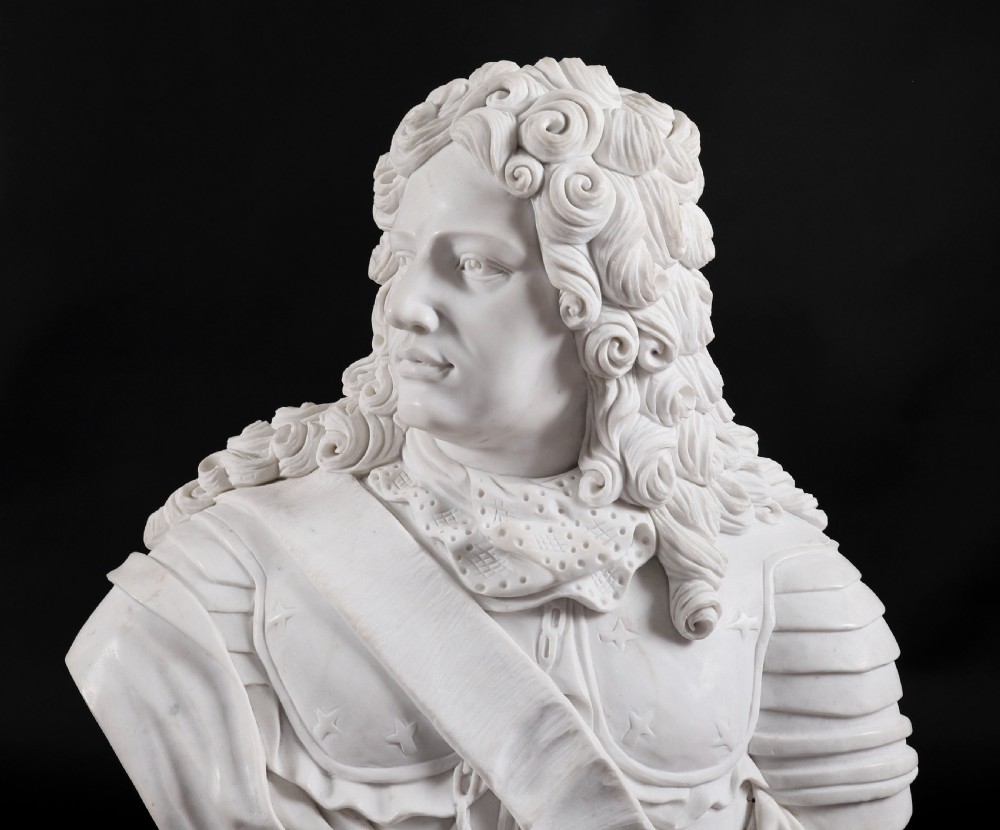 Carved white marble bust depicting a nobleman with long curled hair, lace cravat, and plate armour on a turned circular pedestal. View XIII