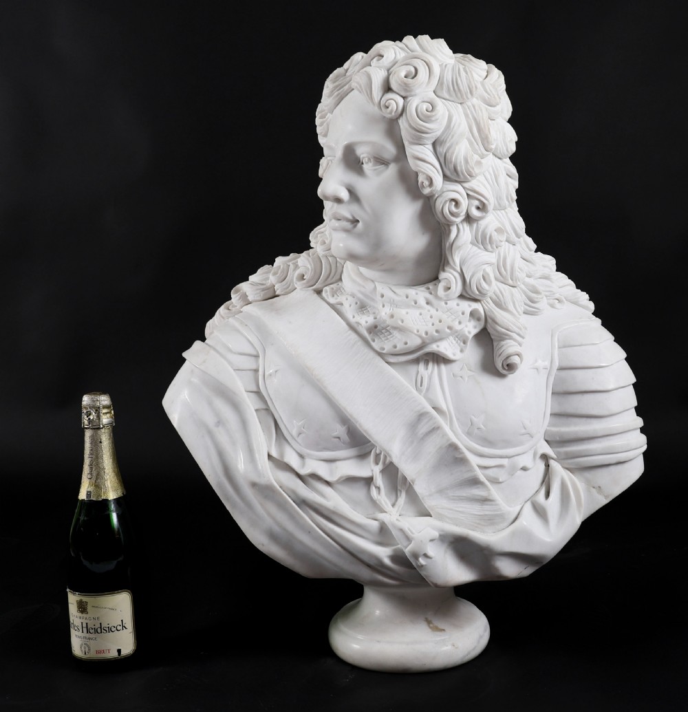 Carved white marble bust depicting a nobleman with long curled hair, lace cravat, and plate armour on a turned circular pedestal. View XIX