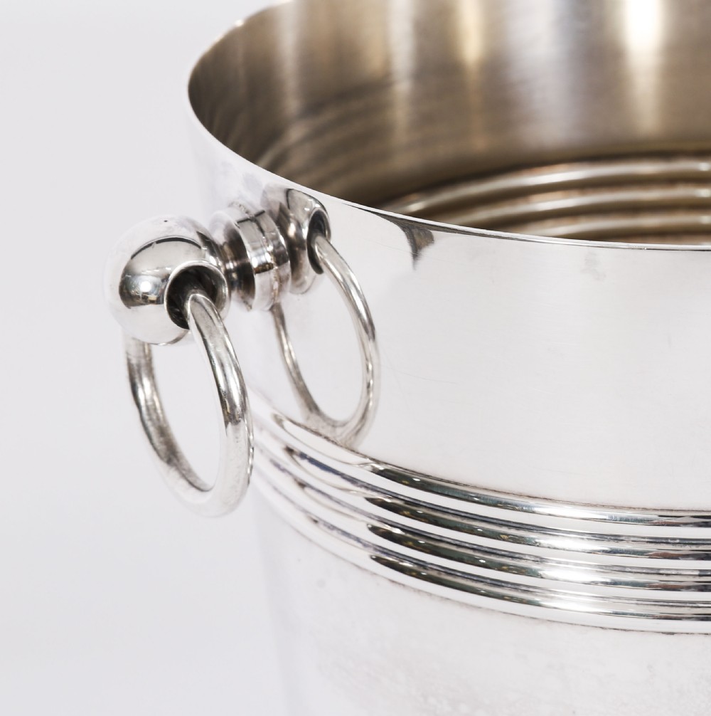 An Art Deco silver-plated champagne cooler featuring reeded horizontal bands and twin drop-ring handles on spherical mounts. View IV
