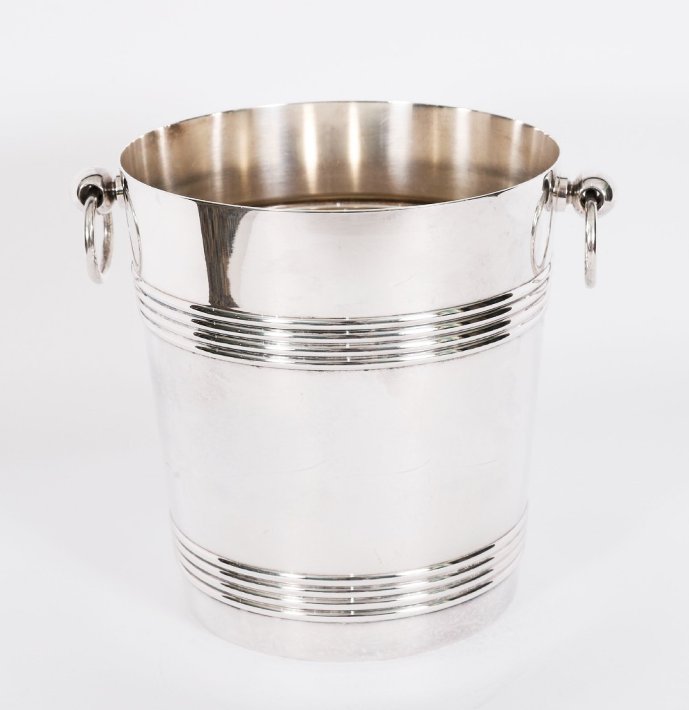 An Art Deco silver-plated champagne cooler featuring reeded horizontal bands and twin drop-ring handles on spherical mounts. View VI