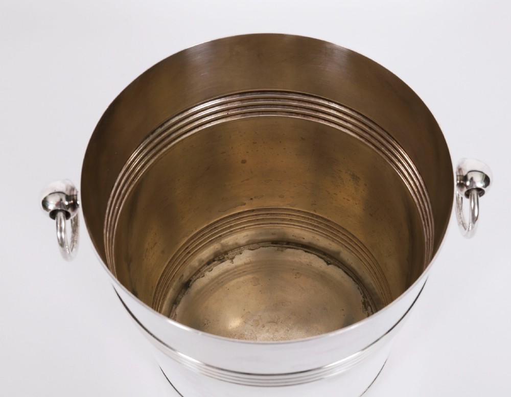 An Art Deco silver-plated champagne cooler featuring reeded horizontal bands and twin drop-ring handles on spherical mounts. View XI
