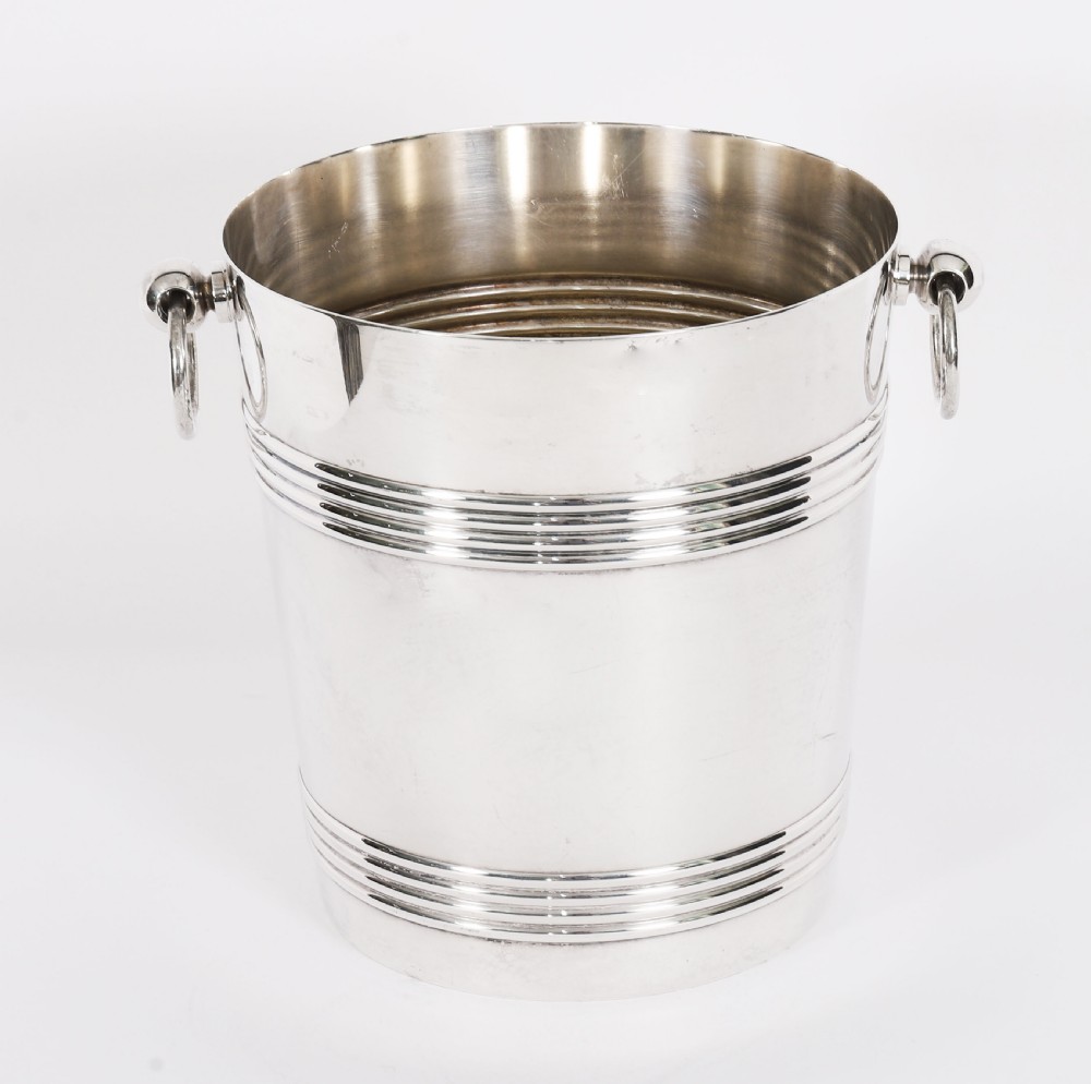 An Art Deco silver-plated champagne cooler featuring reeded horizontal bands and twin drop-ring handles on spherical mounts. View XVI