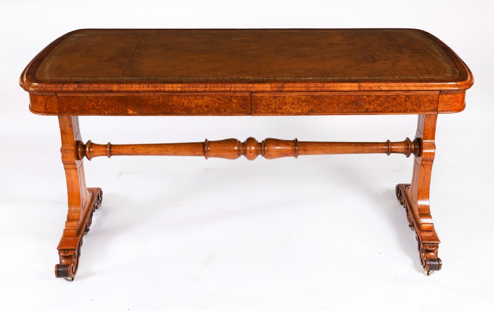A 19th-century Victorian pollard oak writing table featuring a brown leather inset top, carved trestle end supports, a turned central stretcher, and scroll feet on brass castors. View II