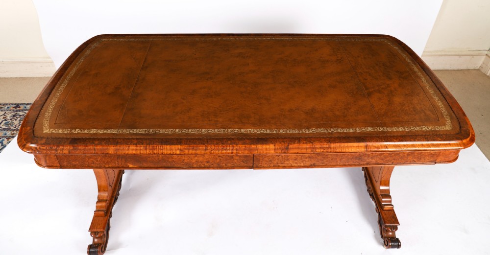 A 19th-century Victorian pollard oak writing table featuring a brown leather inset top, carved trestle end supports, a turned central stretcher, and scroll feet on brass castors. View IV